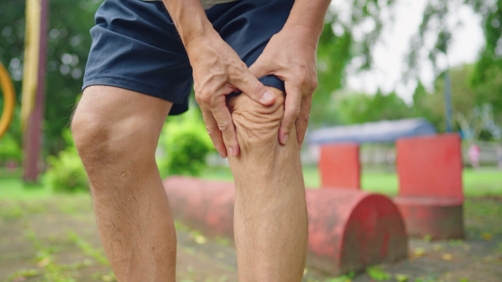 middle aged man grabbing knee in pain